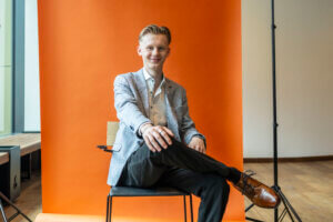 Fotoshooting während der Ausbildung zum Immobilienkaufmann, Collin sitzend vor einer Leinwand