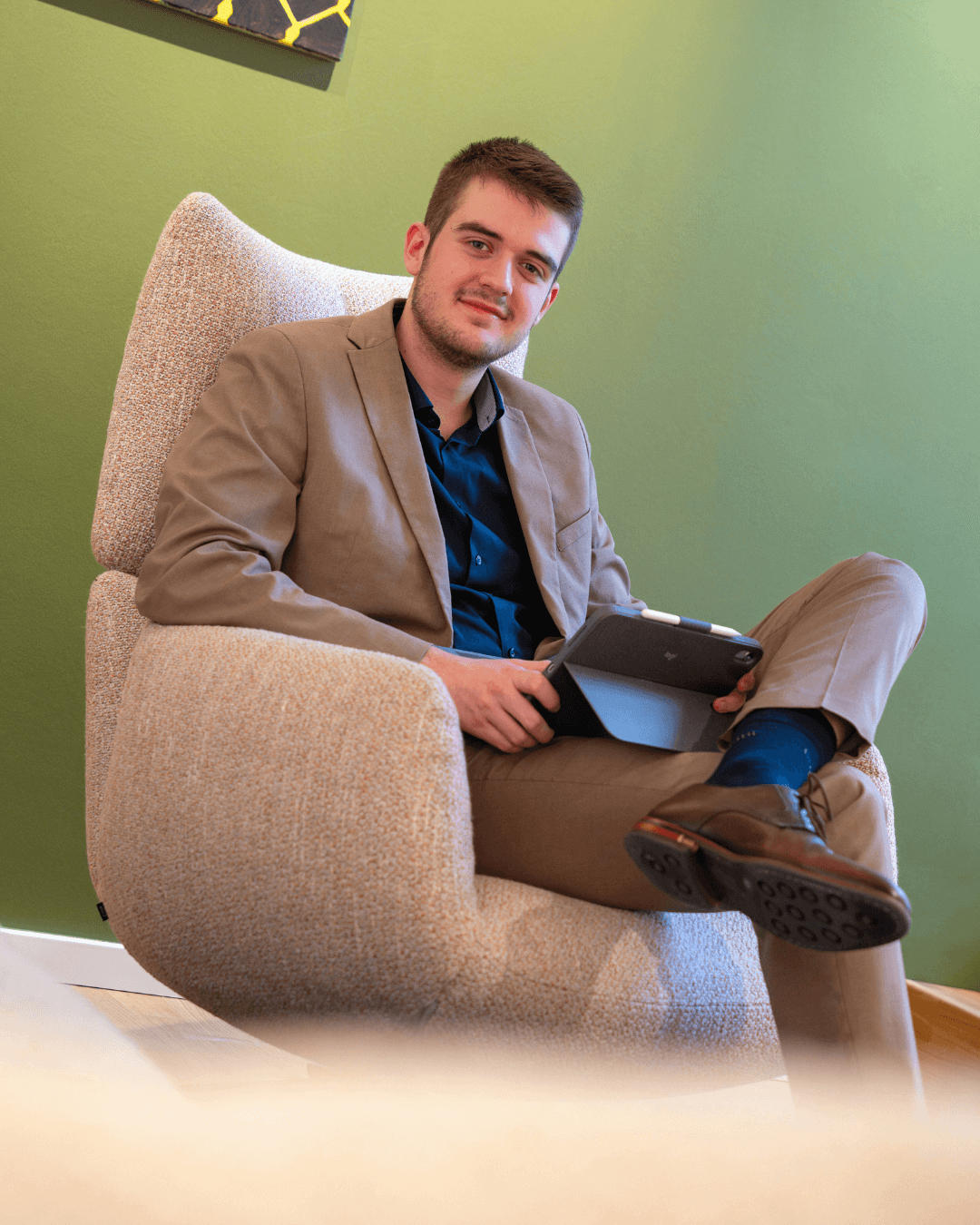 Auszubildender mit Tablet in der Hand, sitzend auf einem Sessel