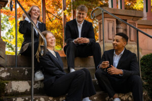 Vier Azubis sitzend auf Treppe, lachen gemeinsam