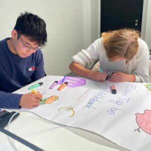Zwei Azubis malen auf einem Plakat für eine Flipchart