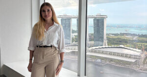 Junge Frau vor Fenster mit Blick auf die Marina Bay während ihrer Hospitation bei der DZ BANK in Singapur