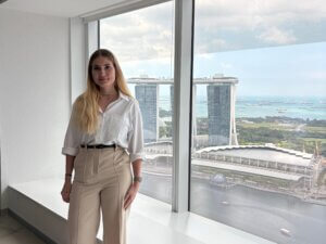 Junge Frau vor Fenster mit Blick auf die Marina Bay während ihrer Hospitation bei der DZ BANK in Singapur
