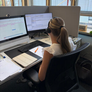 Auszubildende im QSC: mit Headset am Schreibtisch sitzend