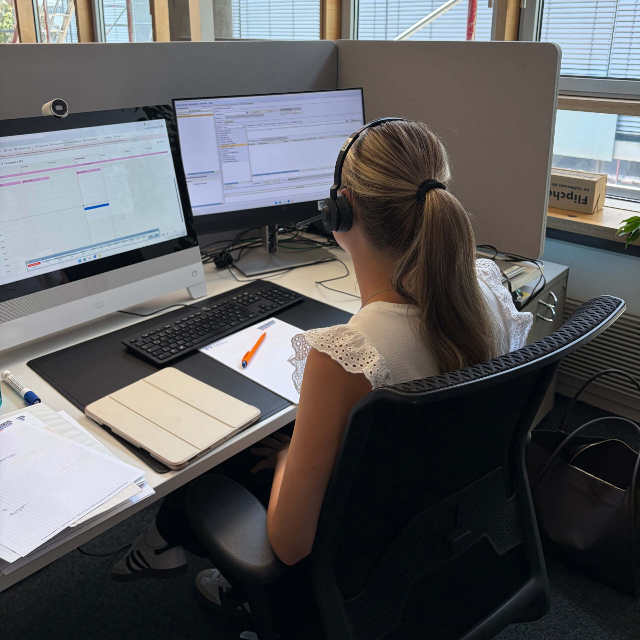 Auszubildende im QSC: mit Headset am Schreibtisch sitzend